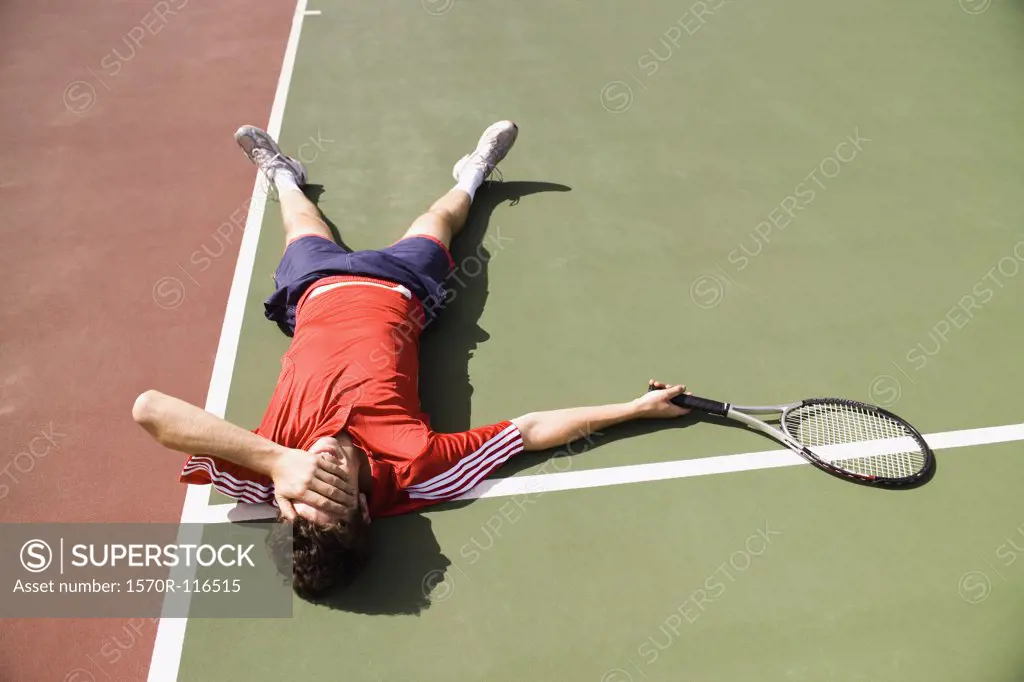 A tennis player lying down on the tennis court