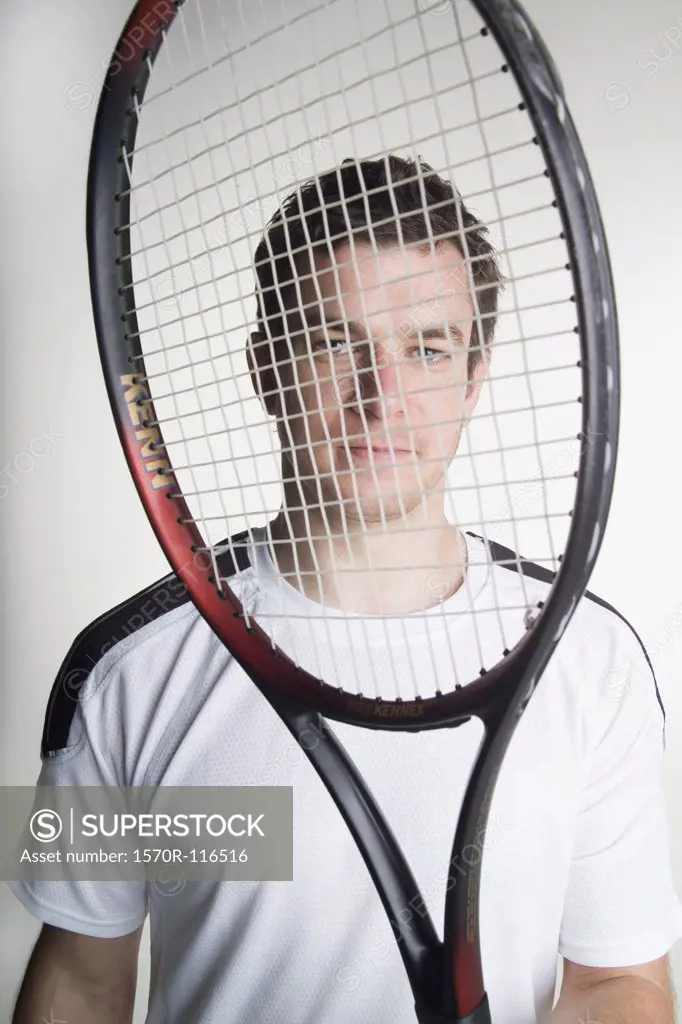 A tennis playing holding his tennis racquet in front of his face