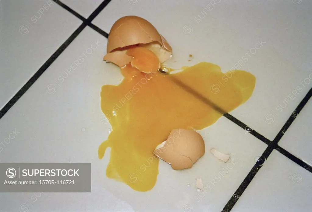 A broken egg on a tiled floor
