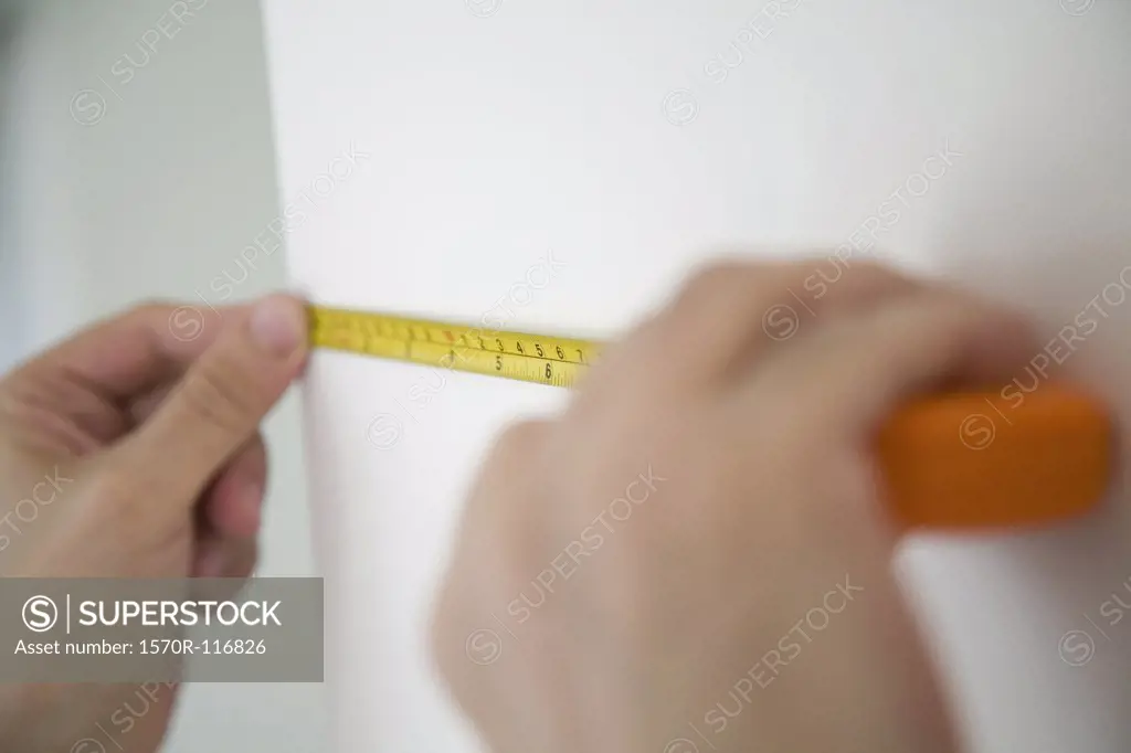 Close up of hands measuring a wall