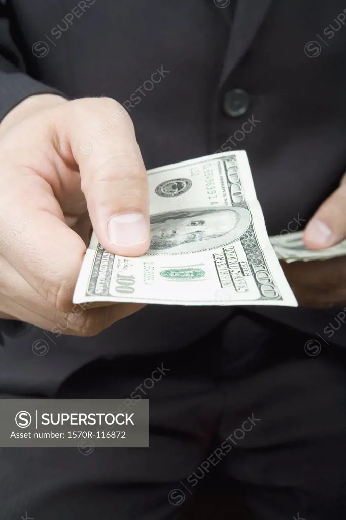 A businessman offering a hundred dollar bill