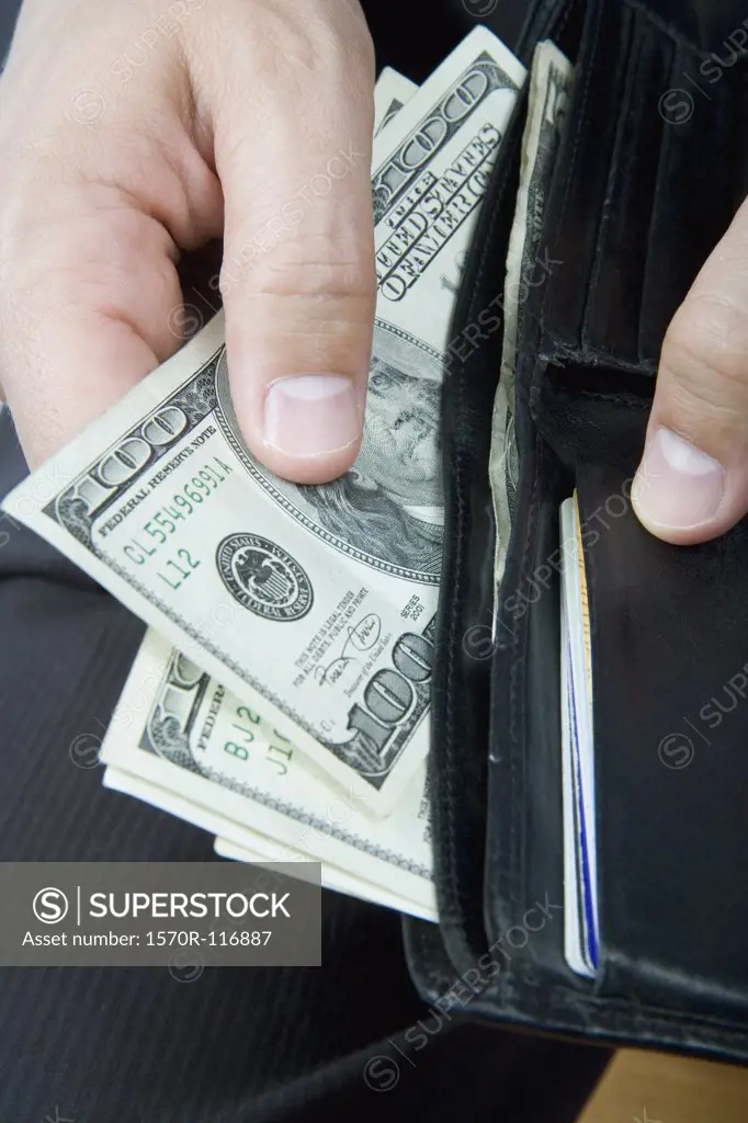 A businessman taking US bank notes from his wallet