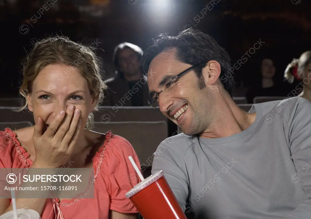 A mid adult couple laughing in a movie theater