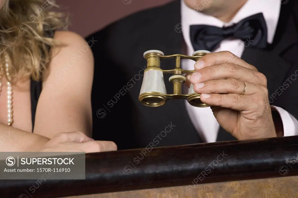 Detail of a couple with binoculars in a theater box