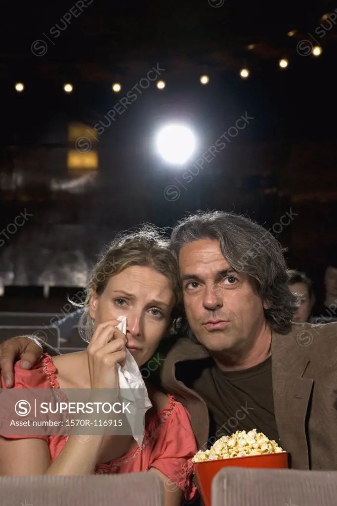 A woman crying whilst sitting with a man in a movie theater