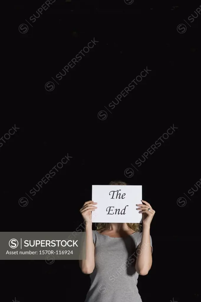 A woman holding a sign for 'The End'