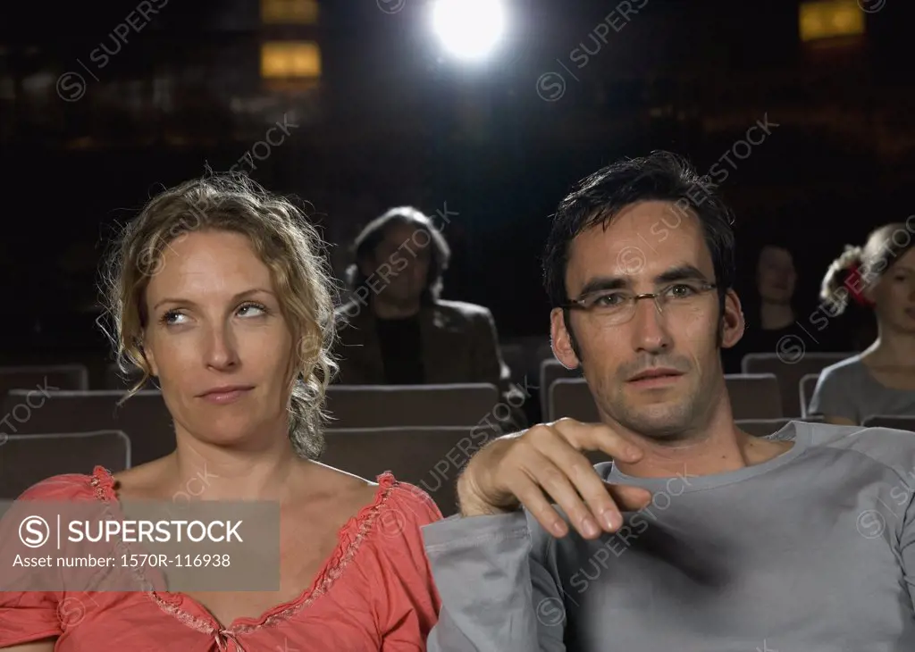 A woman rolling her eyes whilst sitting next to a man in a movie theater
