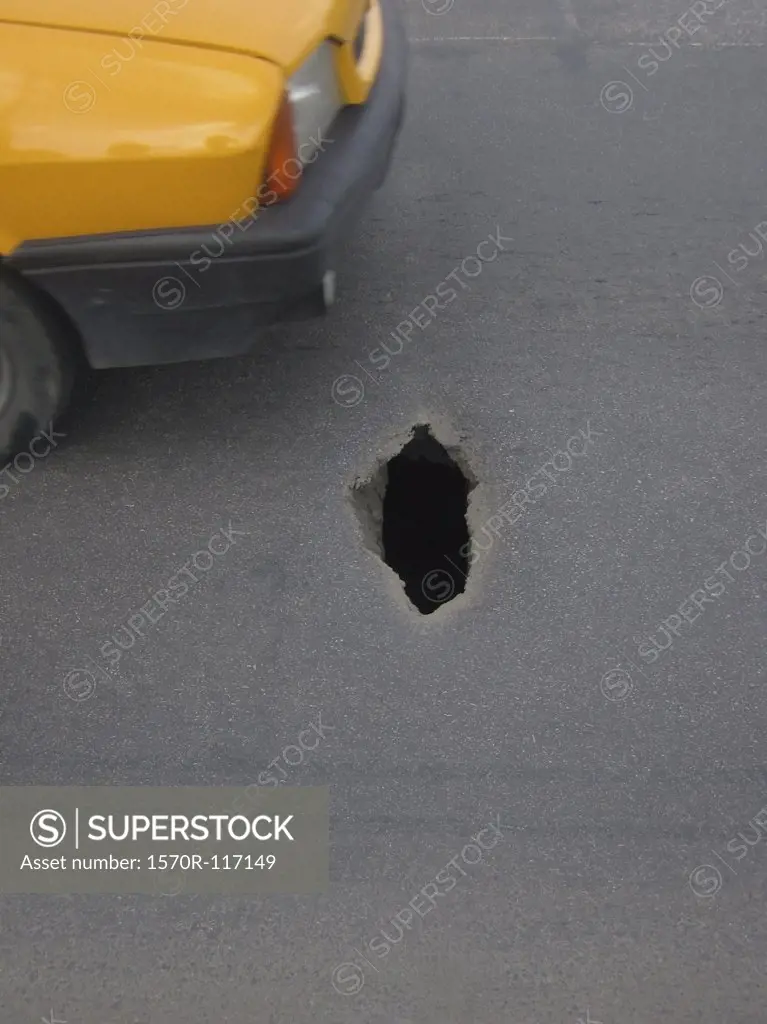 A car driving near a hole in the street
