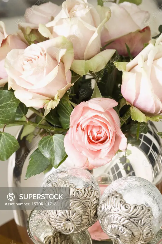A bouquet of pale pink roses in a silver vase
