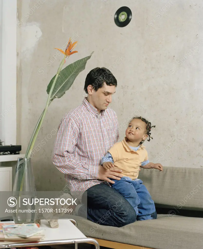 A man kneeling with a toddler on a sofa