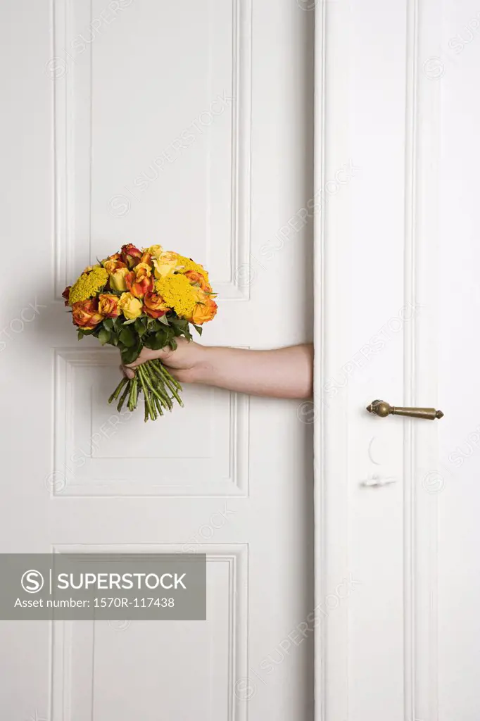 A man holding a bunch of flowers inside a door