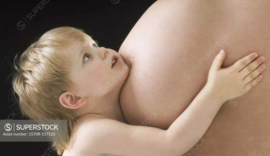 A young boy with his arms around his pregnant mother