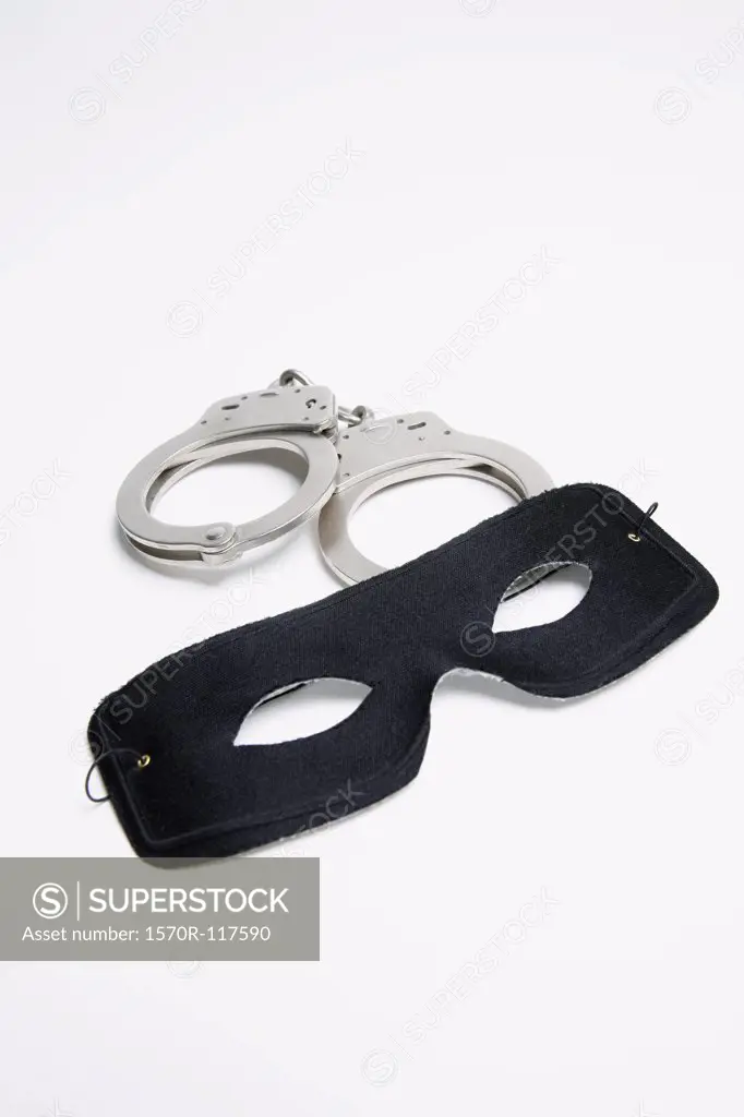 A pair of handcuffs and a black mask