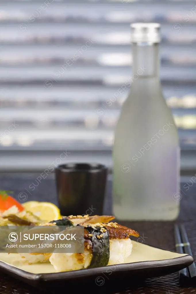 Nigiri sushi in front of a bottle of sake
