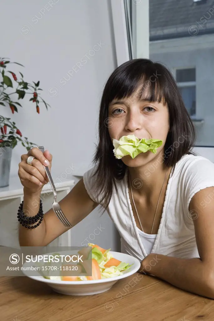 A woman sitting at a table and eating a salad