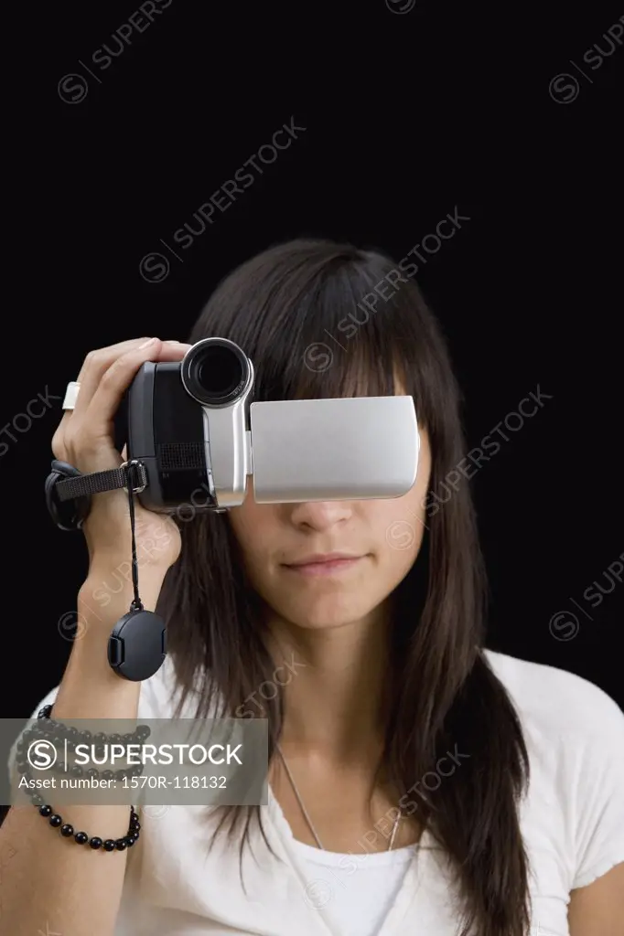 A young woman holding a video camera in front of her face