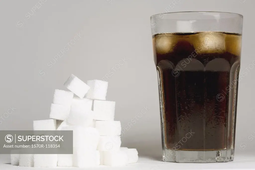 A glass of coke and a heap of sugar cubes