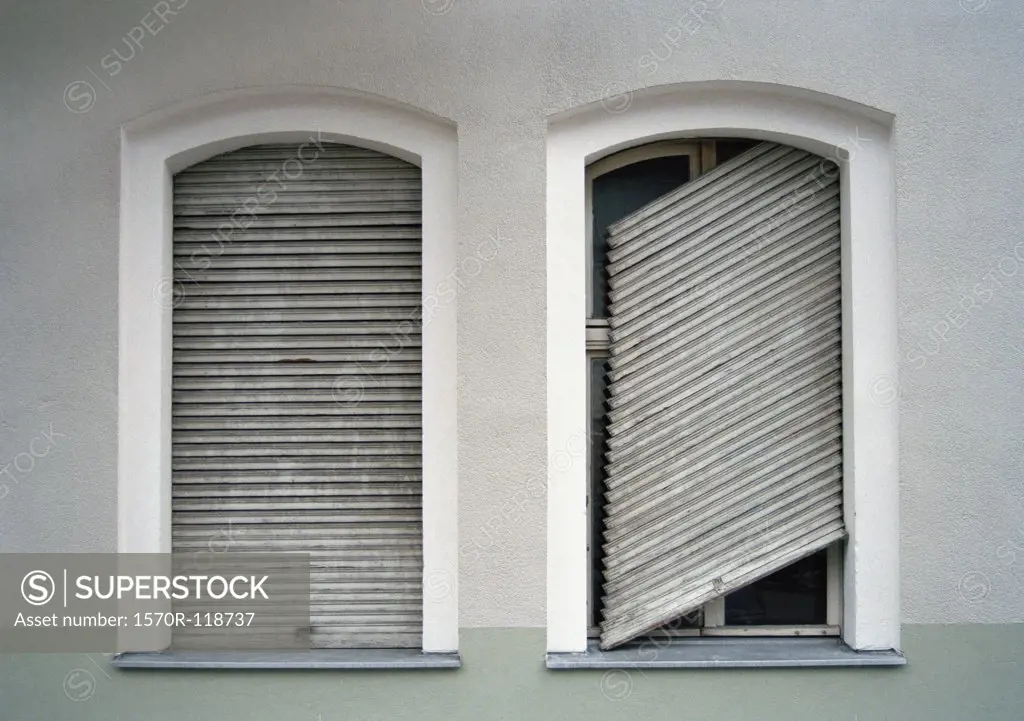 Two shuttered windows with one shutter broken