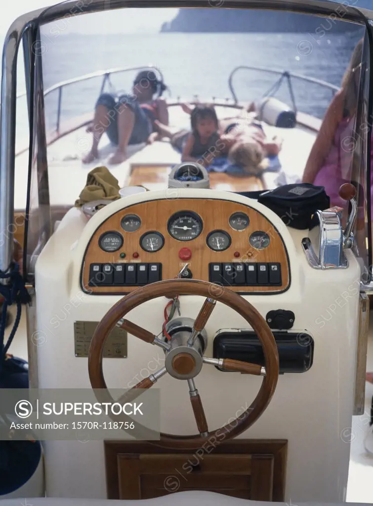 The helm of a boat and people sunbathing on deck