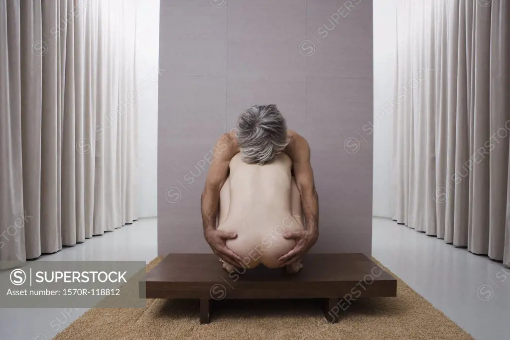 A naked man with his arms around a naked woman crouching