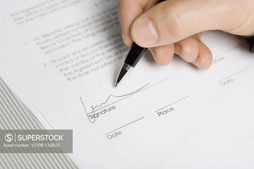 A hand signing a document