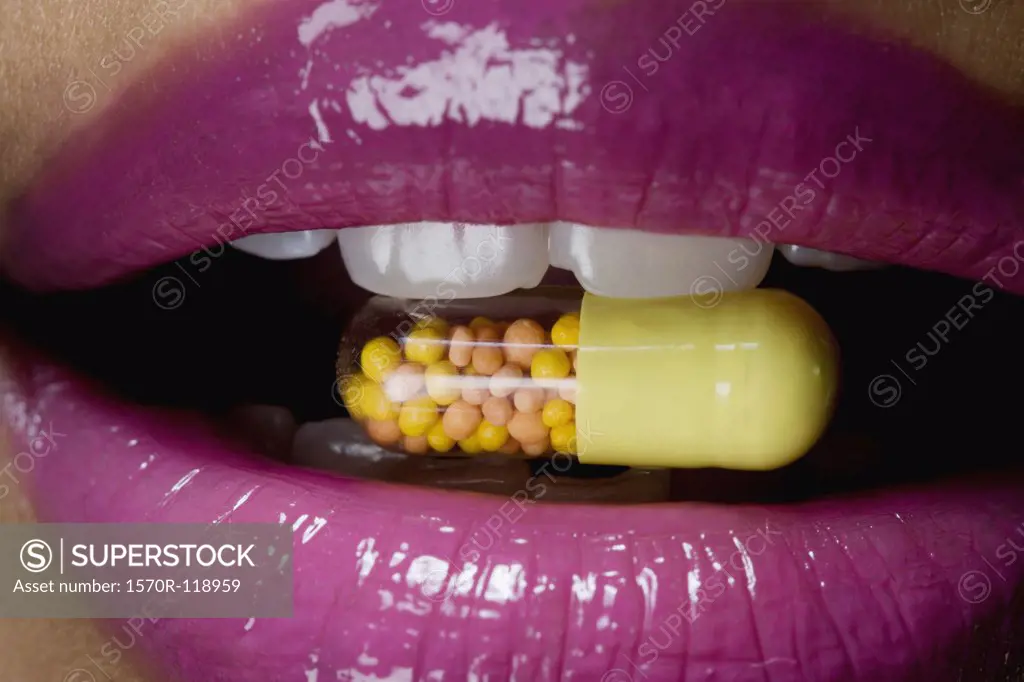 A vitamin pill inside a woman's mouth
