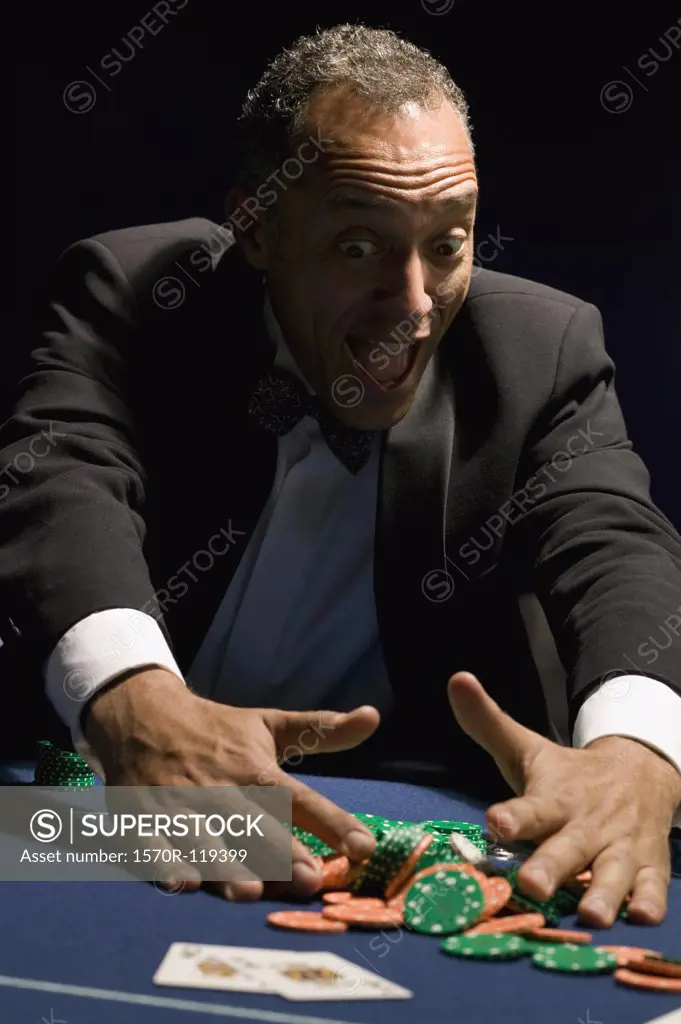 Ecstatic man gathering winning chips at casino table