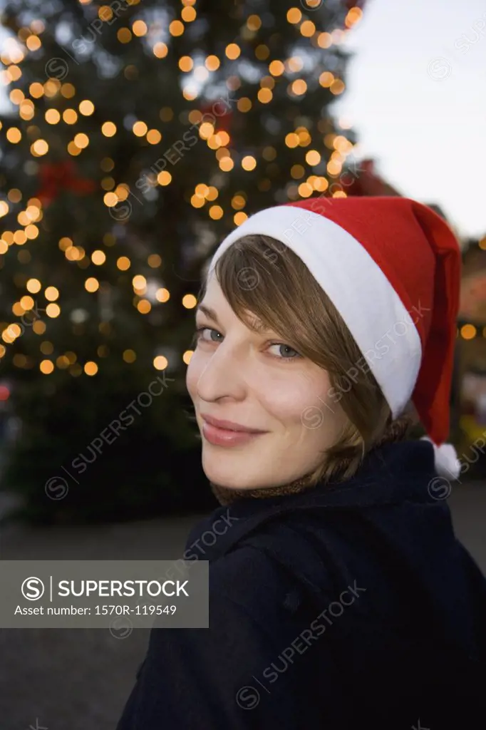 Woman wearing a Santa hat in front of a Christmas tree