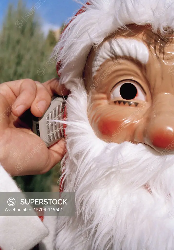 Man wearing a mask of Santa Claus and holding a mobile phone
