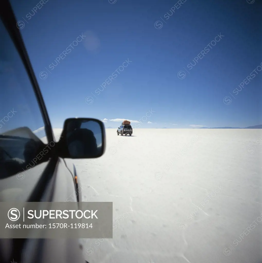 SUV's driving across salt flat, Salar de Uyuni, Bolivia