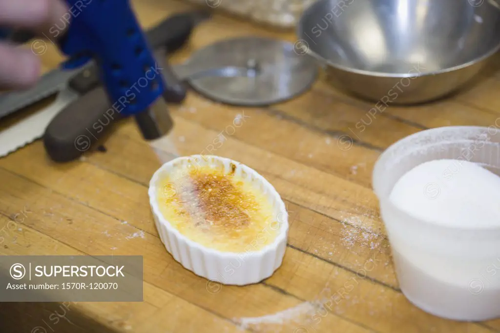 Chef using a kitchen torch to make creme brulee