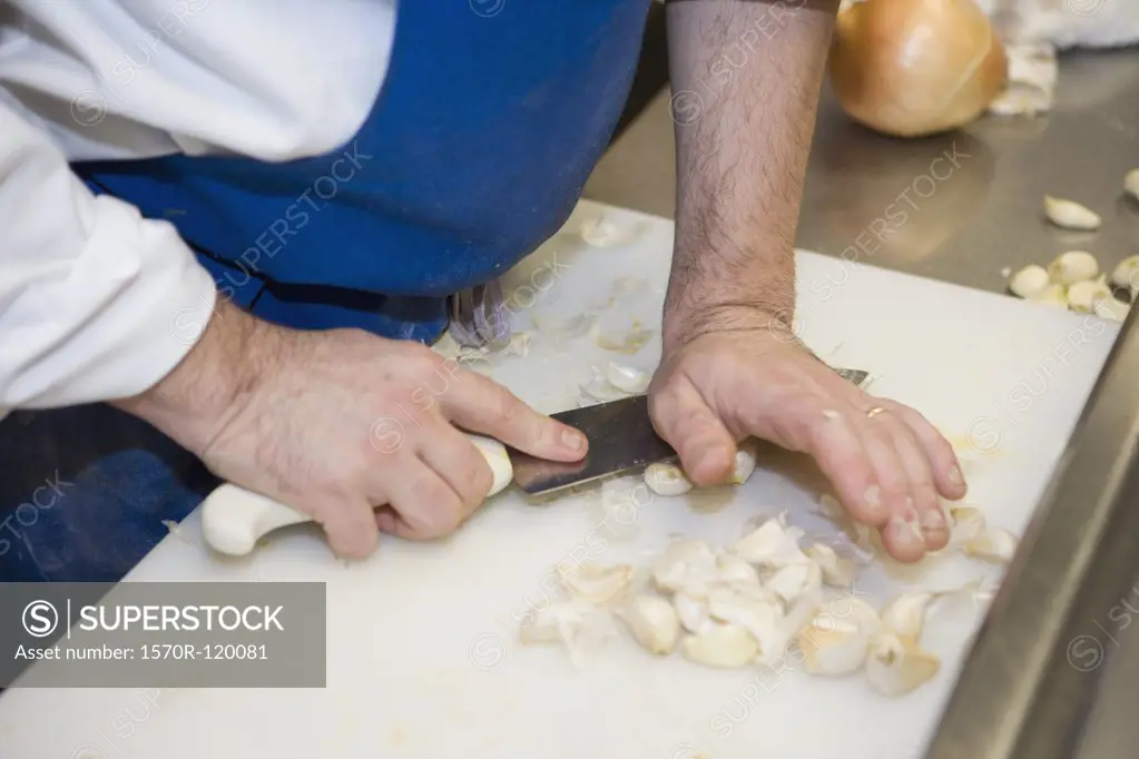Chef squashing cloves of garlic