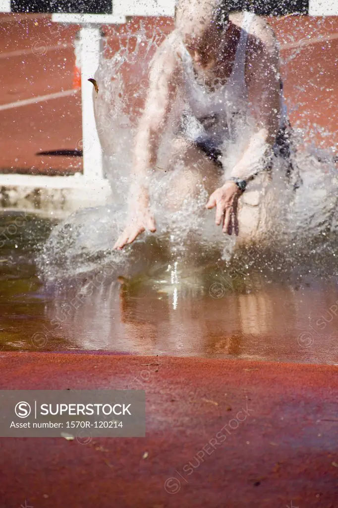 Man falling in water jump during steeplechase event