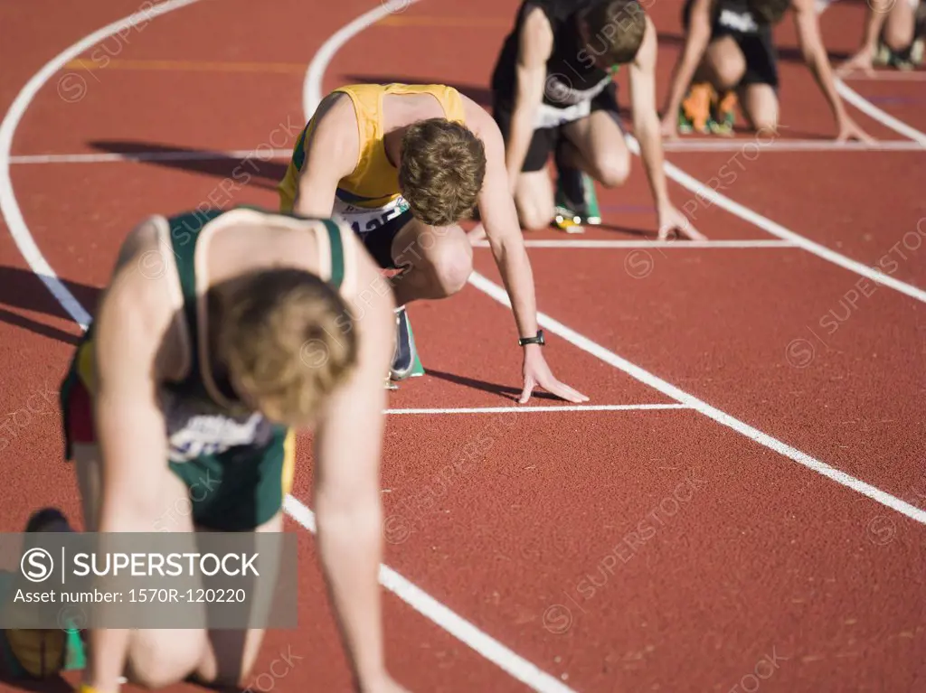 Group of male athletes in starting blocks on a running track