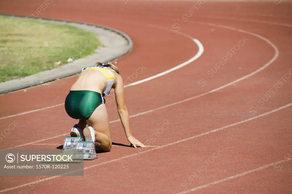 Female athlete in starting blocks on a running track