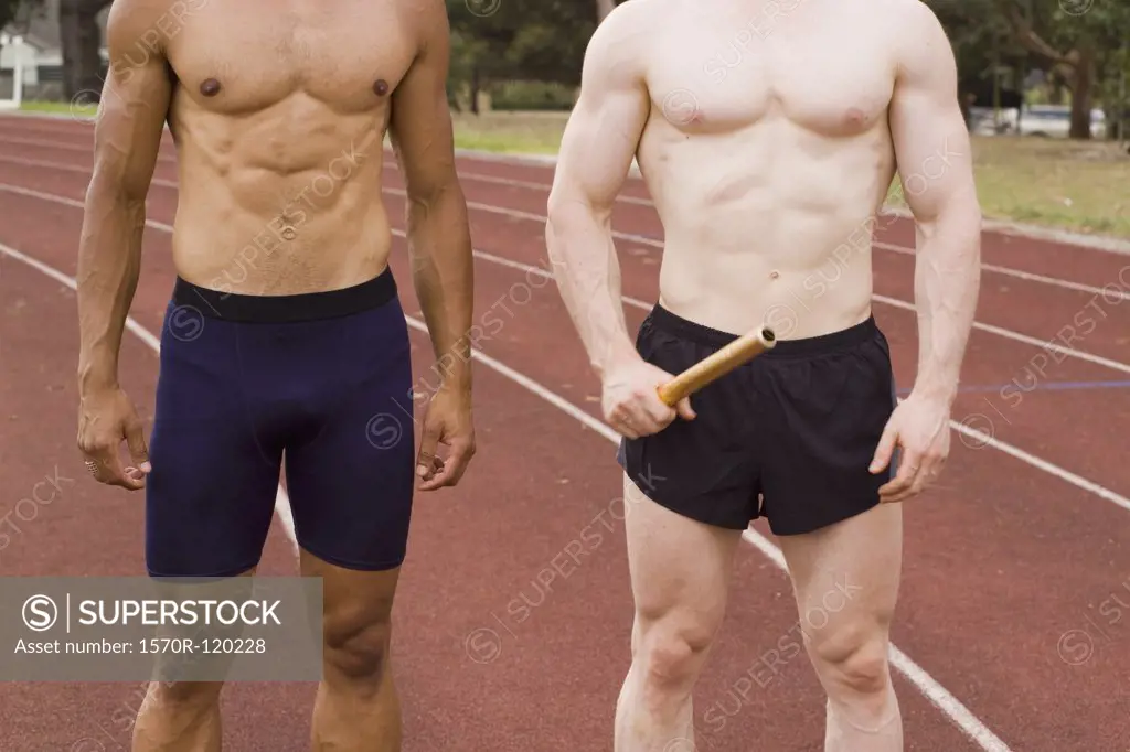 Two male athletes standing side by side on a running track