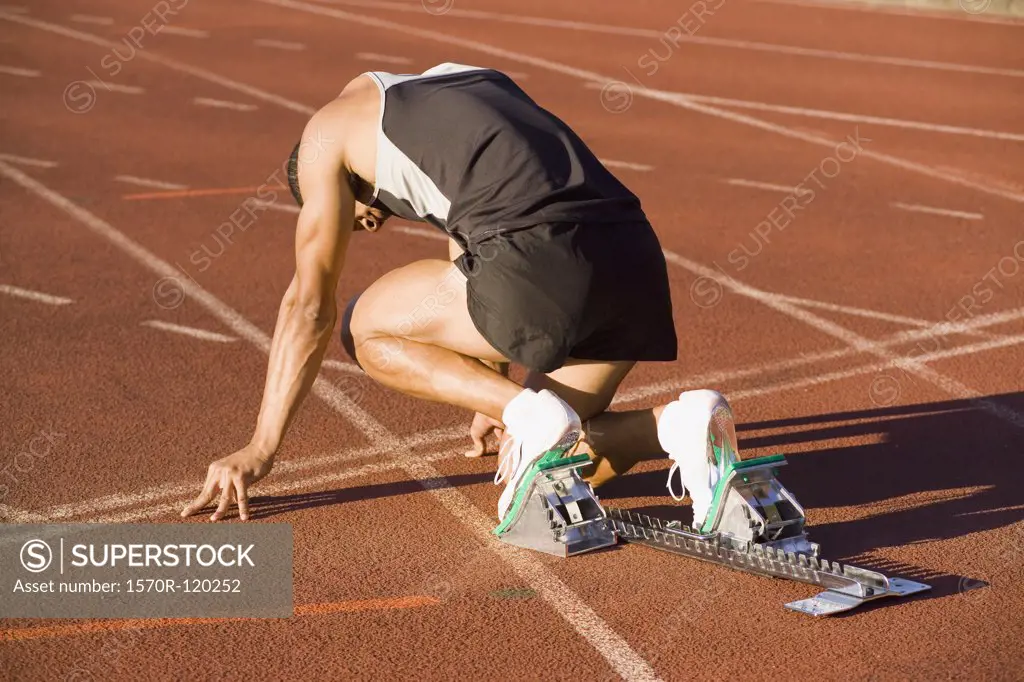 Male athlete in starting blocks on a running track