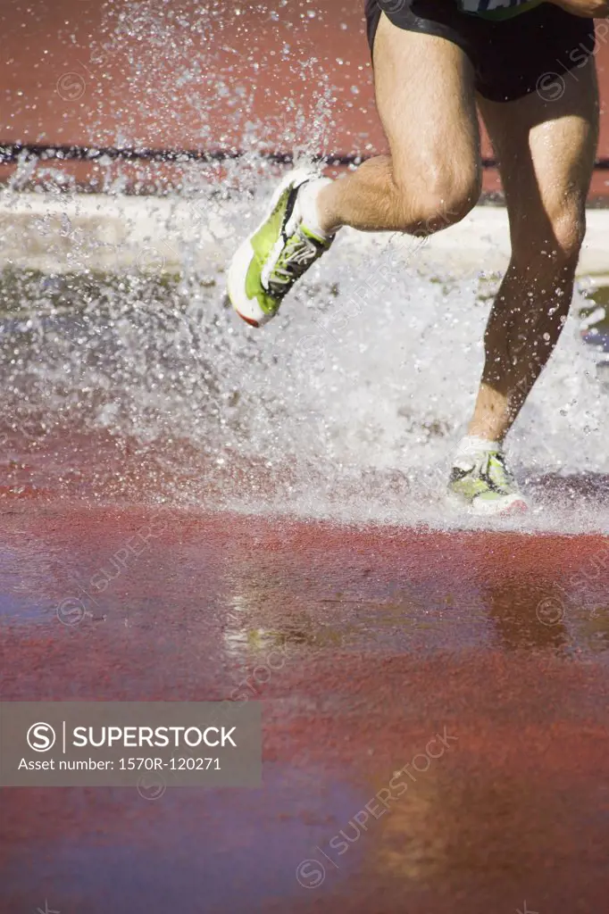 Man running through water jump during steeplechase event