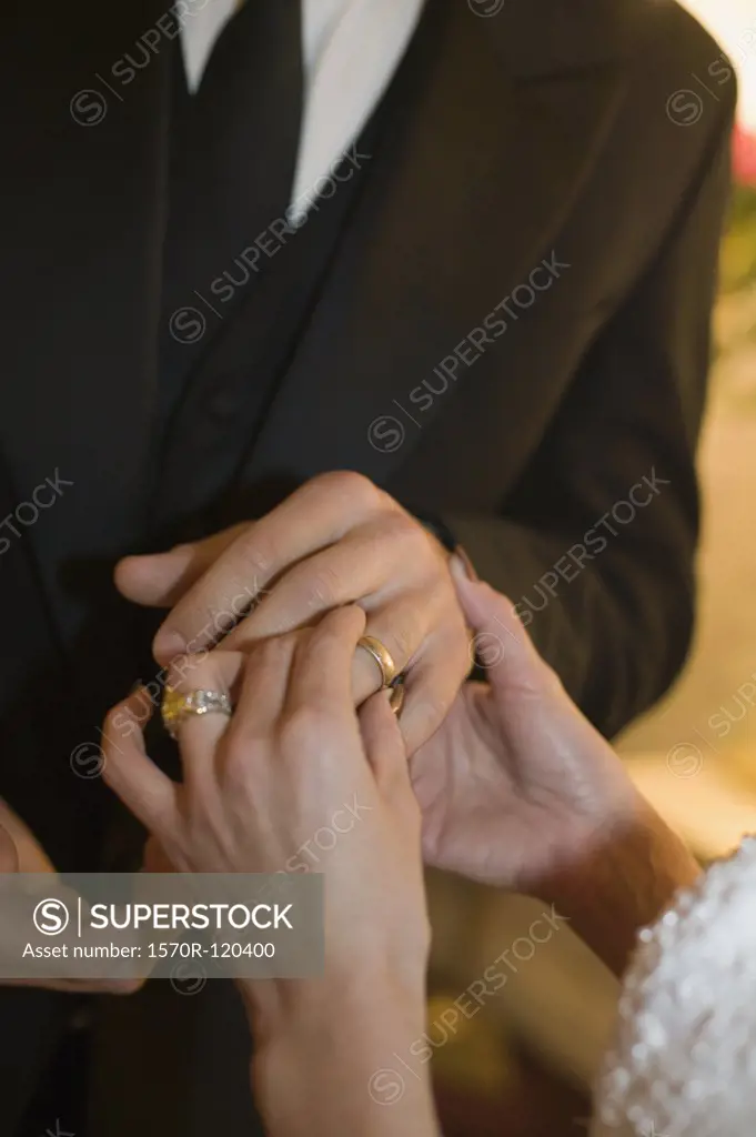 Woman putting a wedding ring on a man's finger