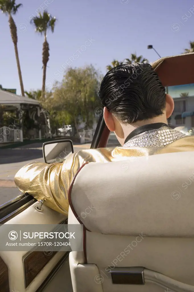 Elvis impersonator driving a vintage convertible car