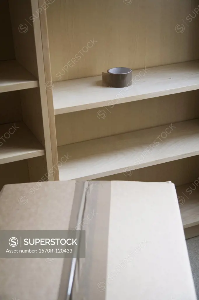 Packing box next to an empty bookshelf