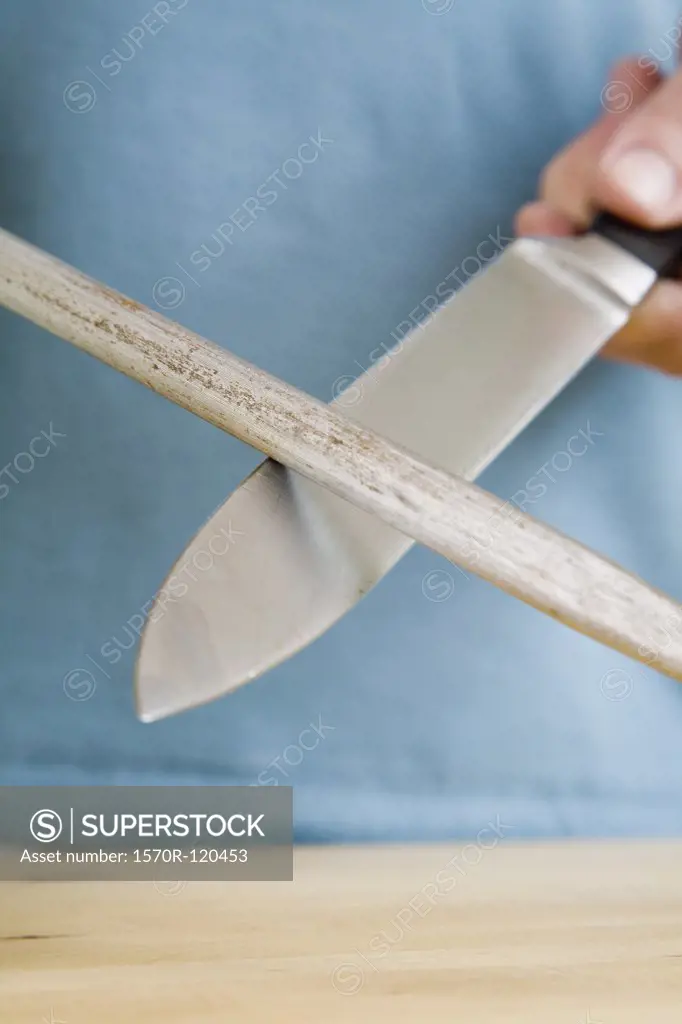 A man sharpening a kitchen knife with a steel