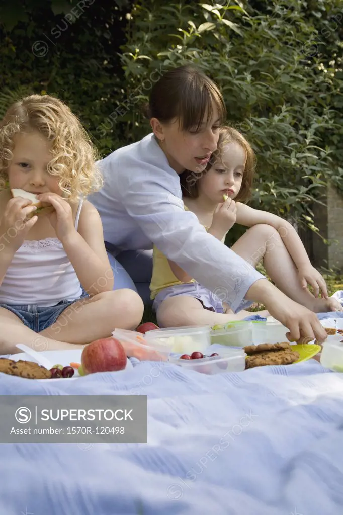 A woman and two girls having a picnic