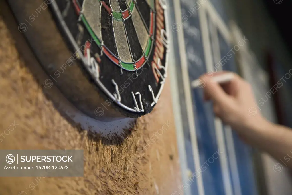 Person keeping score on a blackboard during a game of darts