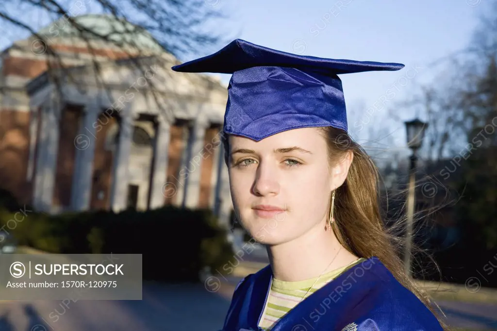 Woman in a graduation gown and mortar board outside of university