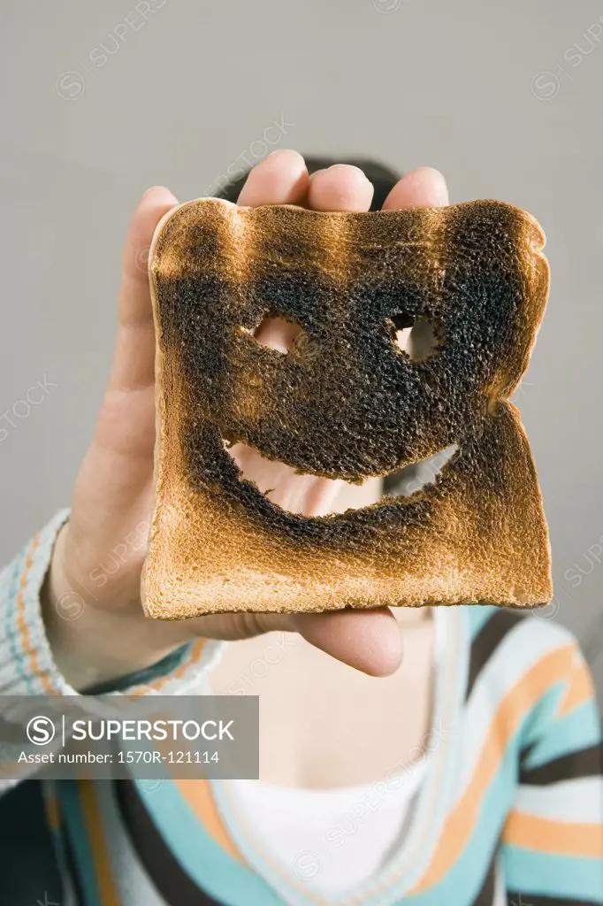 Woman holding burnt toast in front of face