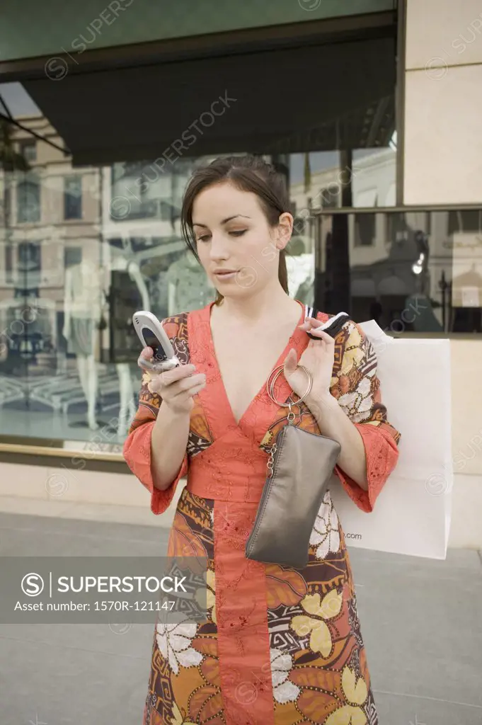 A woman using a mobile phone and holding a purse, Rodeo Drive, Los Angeles, California