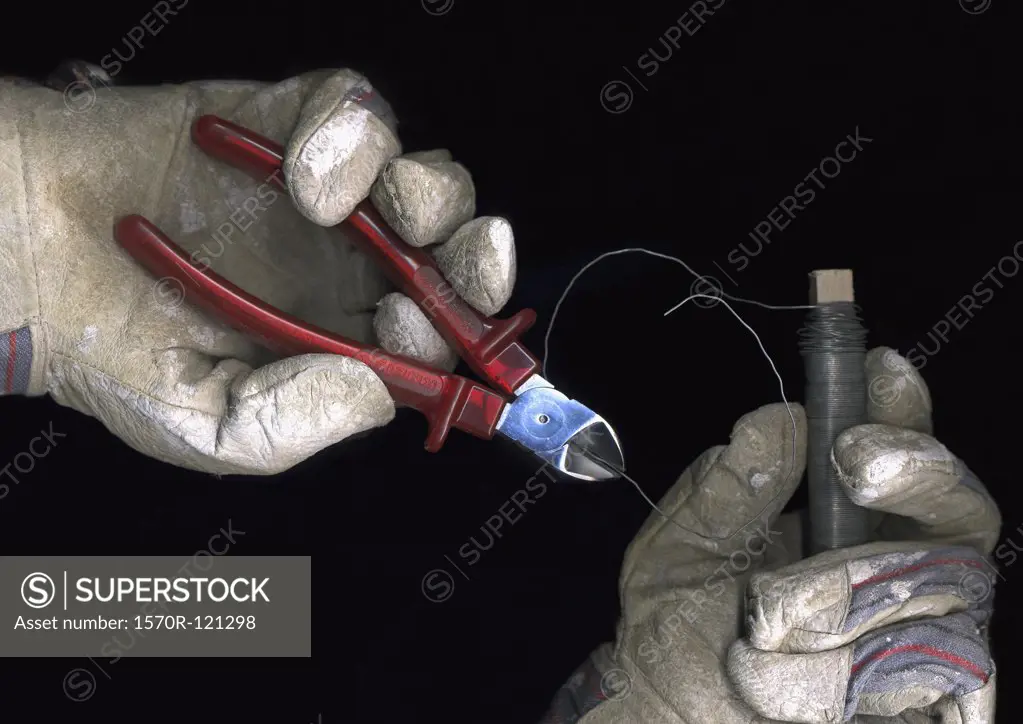 Person wearing work gloves and cutting wire with pliers