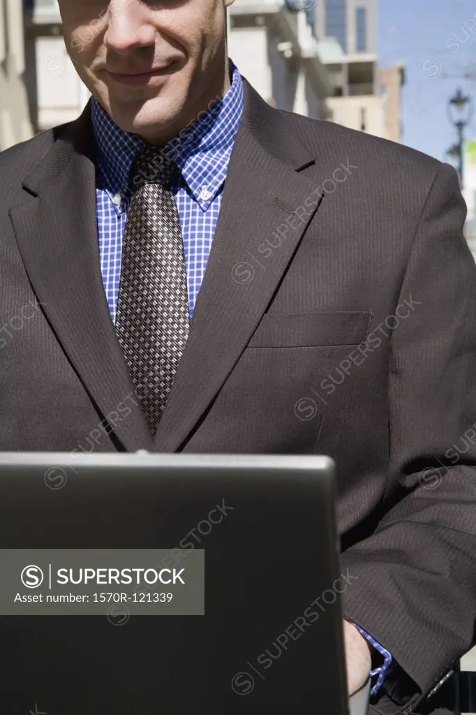 Businessman sitting on an outside bench using a laptop