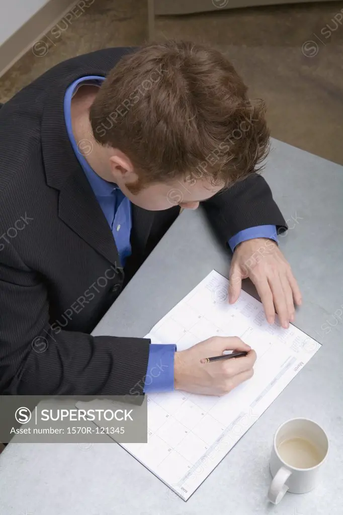 Young businessman sitting at a desk and writing in a personal organizer